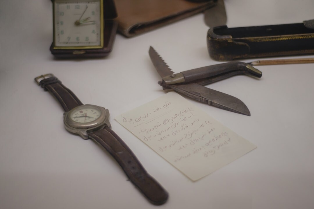 Leather notebook with handwritten notes, a magnifying glass and a pocket watch on a desk