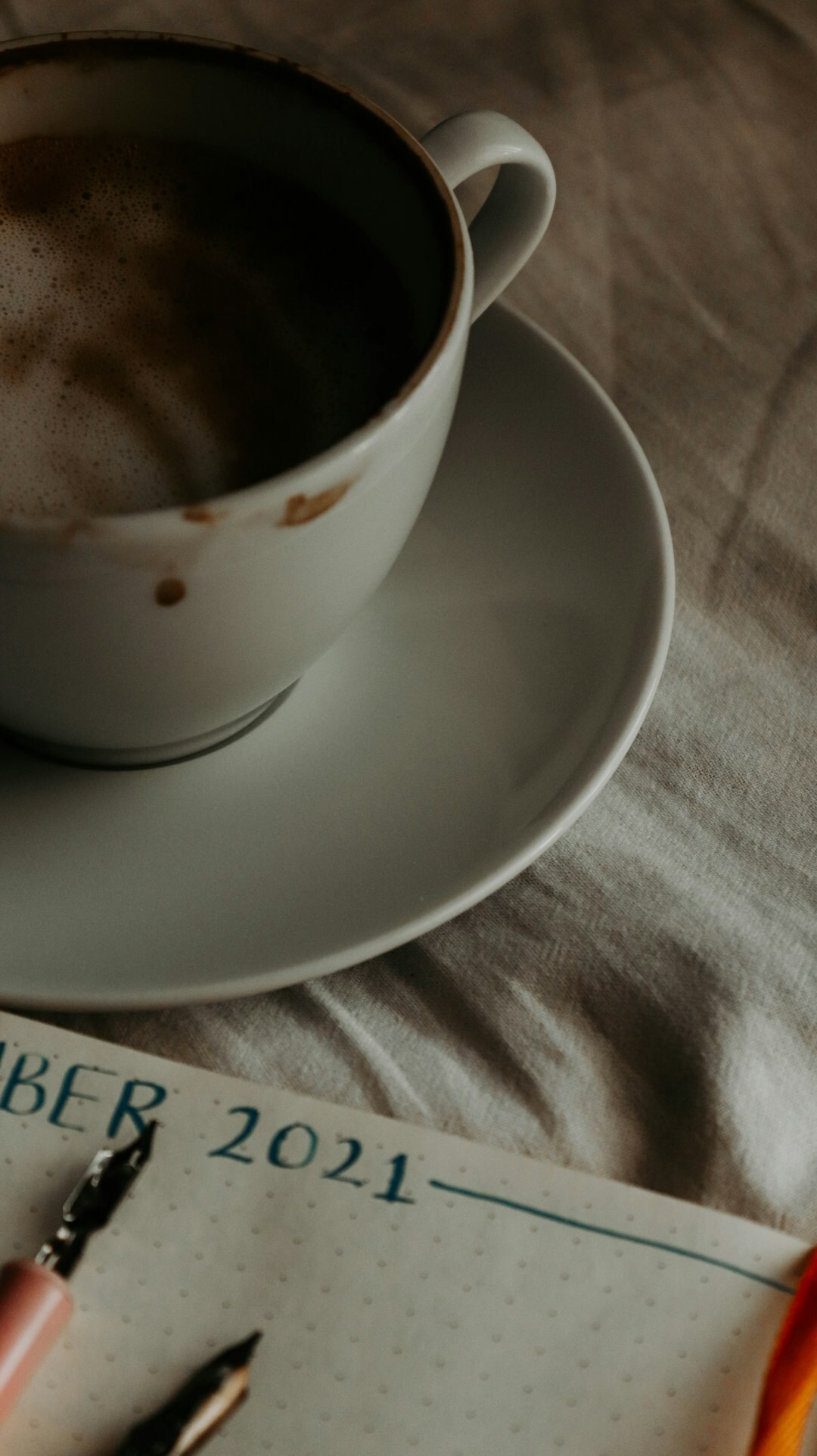 Cup of black coffee beside handwritten manuscript pages and a fountain pen